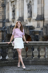 a lady in a pink openwork cardigan and a white skirt